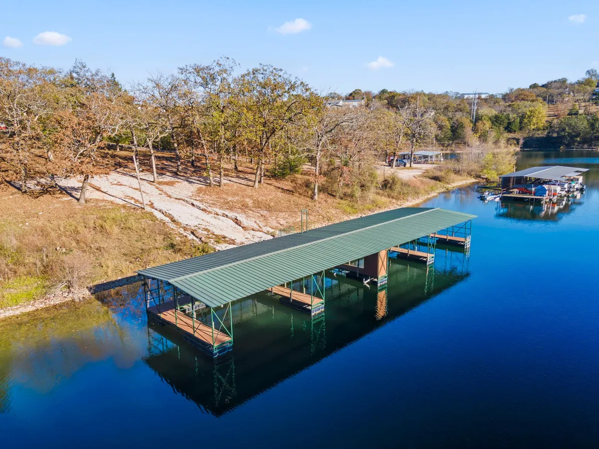 This image features a serene boat dock extending over calm water, framed by lush surrounding trees. The scene invites boating and fishing, with tranquil water perfect for a day outdoors. The setup suggests easy access to the lake for launching boats or casting a fishing line.