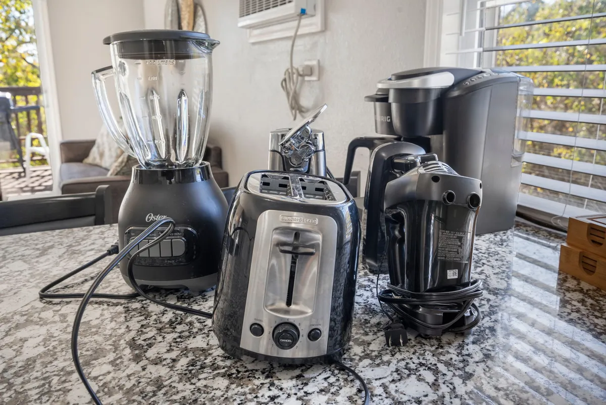 A countertop adorned with small kitchen appliances—blender, toaster, coffee maker, and hand mixer—captures the practical, homey feel of a kitchen ready for everything from breakfast to late-night snacks.
