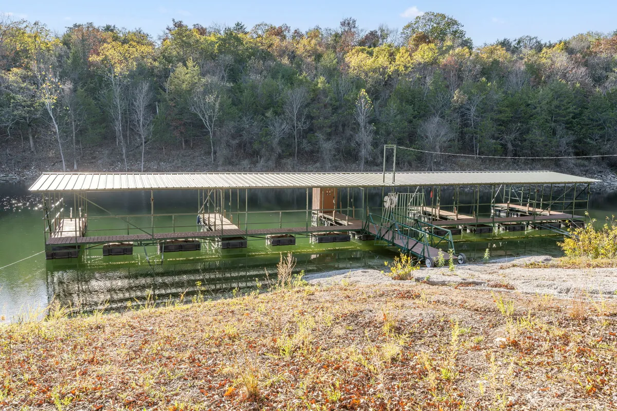 A peaceful boat dock nestled among trees, extending into calm lake waters. The setting is perfect for fishing, boating, or simply taking in a sunset with friends.