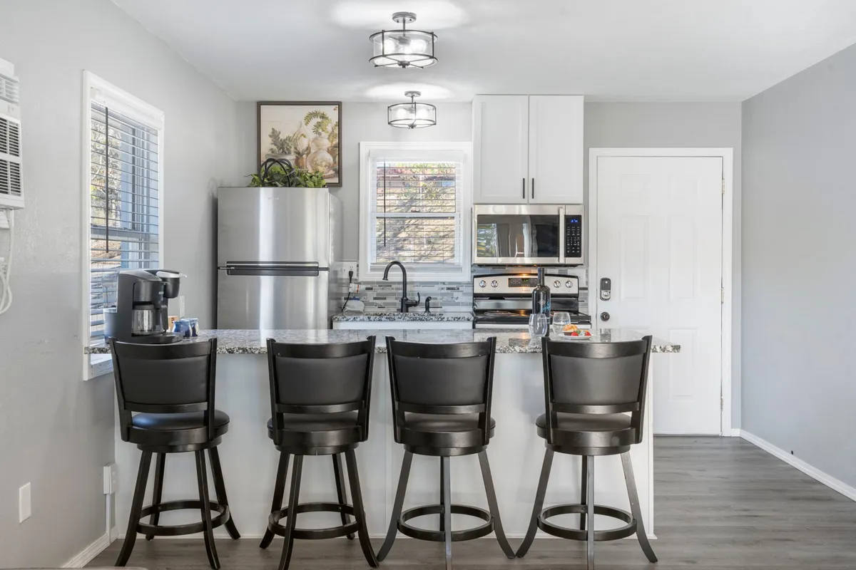 A welcoming kitchen scene with modern stainless steel appliances, a spacious kitchen island with bar stools, and decorative artwork. The open layout invites conversation and provides ample workspace for meal prep or casual dining.