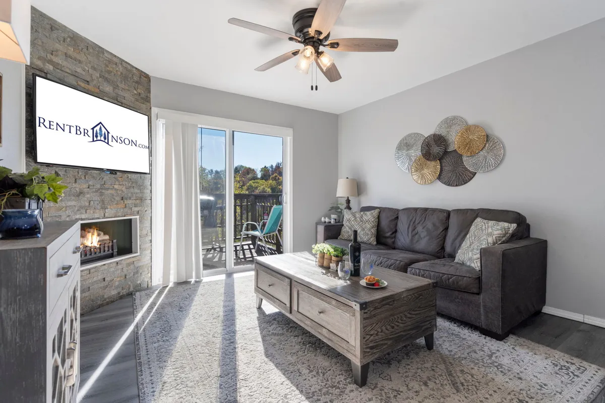 An inviting living area centers around a comfortable sofa, coffee table, fireplace, TV, and decorative wall art. The space exudes warmth and offers a flexible area for both relaxation and extra sleeping accommodation via the sleep sofa.