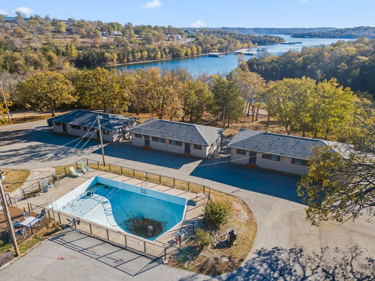 A beautiful exterior shot encompassing a swimming pool, tranquil lake, nearby cabins, and lush trees. The scene blends water recreation, nature, and the property's accommodations, representing the diverse attractions and activities available for guests.
